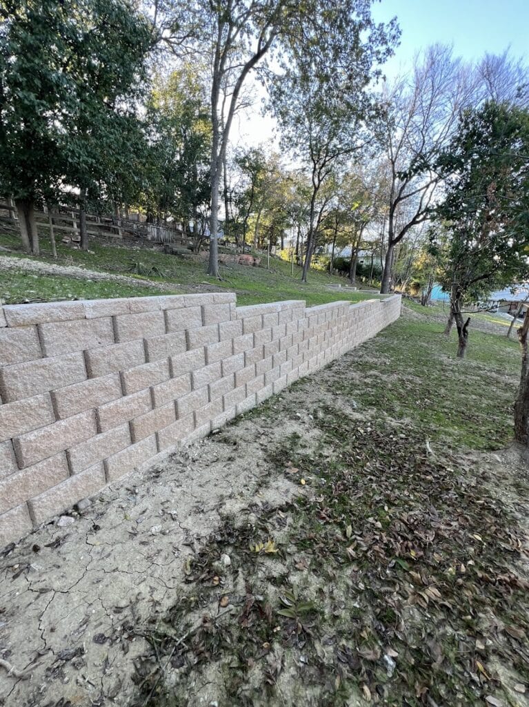 Tiered retaining wall built with modular concrete blocks for soil retention and elevation change management on residential lot