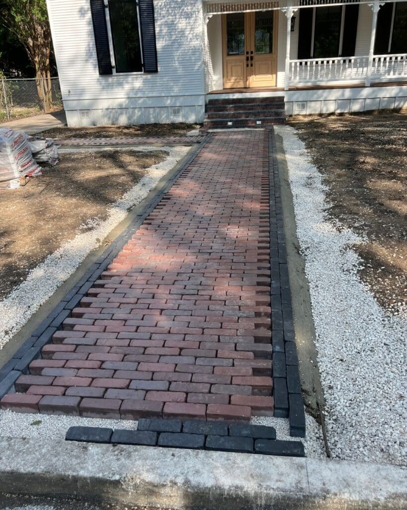 Vision Grounds craftsmen hand-laying Unilock Copthorne pavers in a complex curved layout