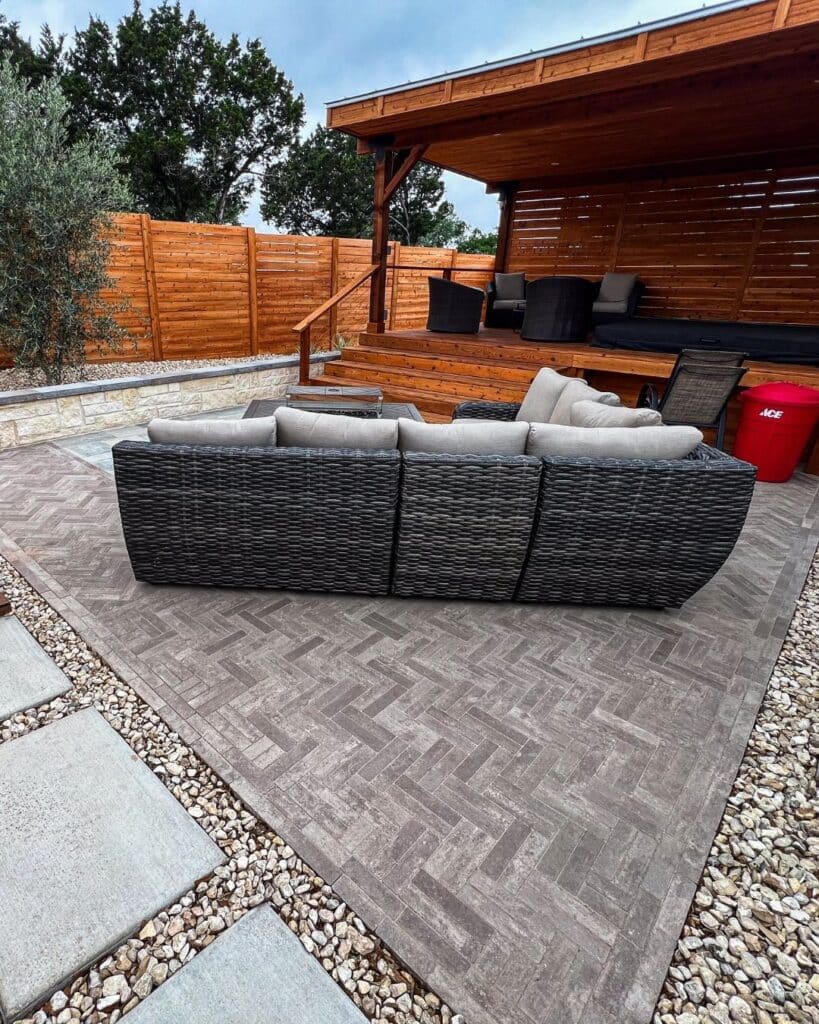 Finished outdoor living space with a limestone retaining wall, modern seating, and native Hill Country landscaping