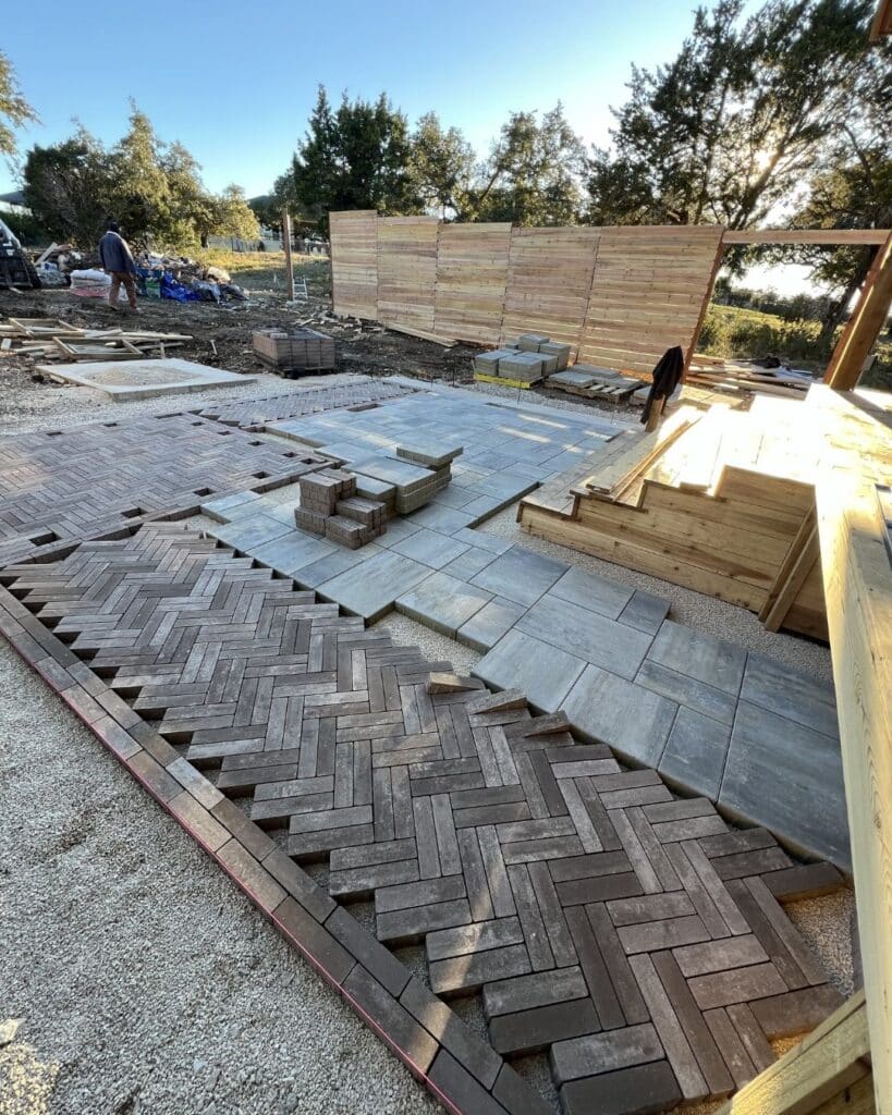 Vision Grounds crew hand-laying a Mattoni herringbone border over an engineered open-grade stone base