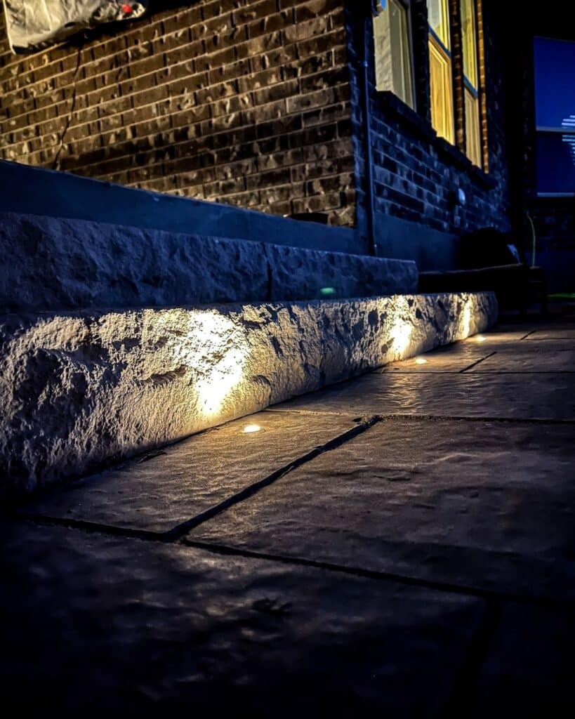 Integrated LED hardscape lighting installed in custom limestone patio steps